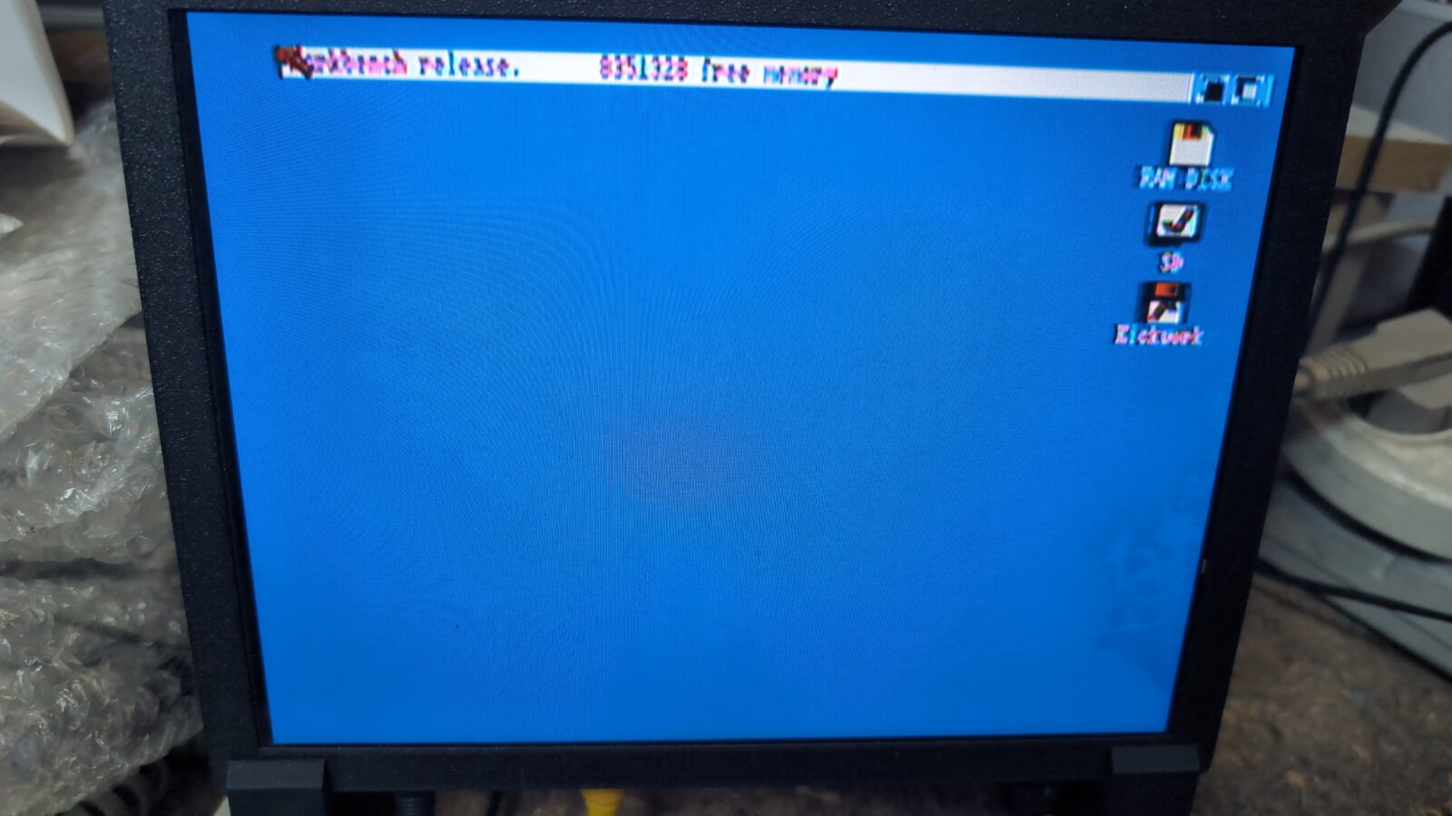 A computer monitor displays a blue desktop screen with a white menu bar at the top and several small icons labeled RAM Disk, CF:, CF:, and Execute on the right side retrohax net